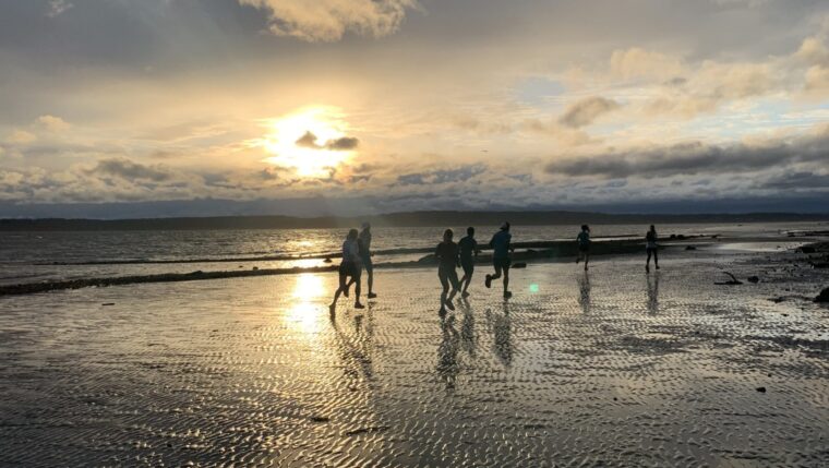 Sunset Team7Hills group run along the low tide beach at Discovery Park. Wednesday night group runs from Seven Hills Running Shop.
