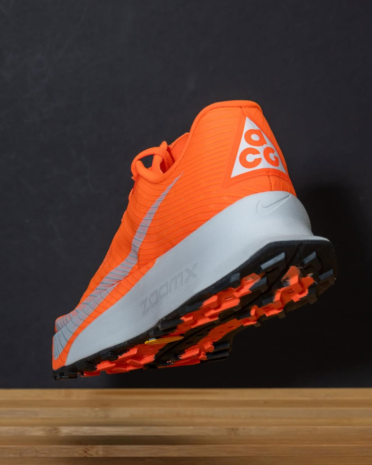 A single bright orange Nike ACG Ultrafly Trail racing trail with the ACG brand logo clearly visible on the heel of the shoe.