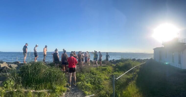 A group of trail runners taking a social break to regroup at the lighthouse in Discovery Park, Seattle.
