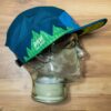Side view of the blue and green Seven Hills Running Shop sublimated performance running cap from Boco Gear.
